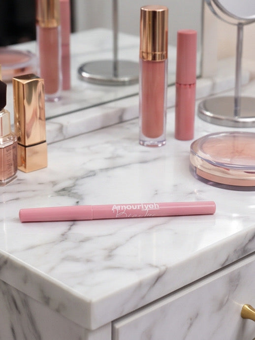 Pink lip products including a lip liner and glosses on a marble surface.